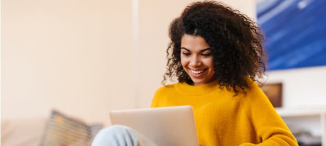 Smiling woman uses a laptop to share files with co-workers on a Dropbox alternative that’s free and open source