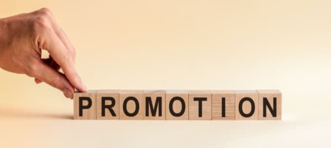 The hand puts a wooden cube with the letter P from the word Promotion.